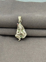 Silver pendant with green and red stones on a gray fabric background