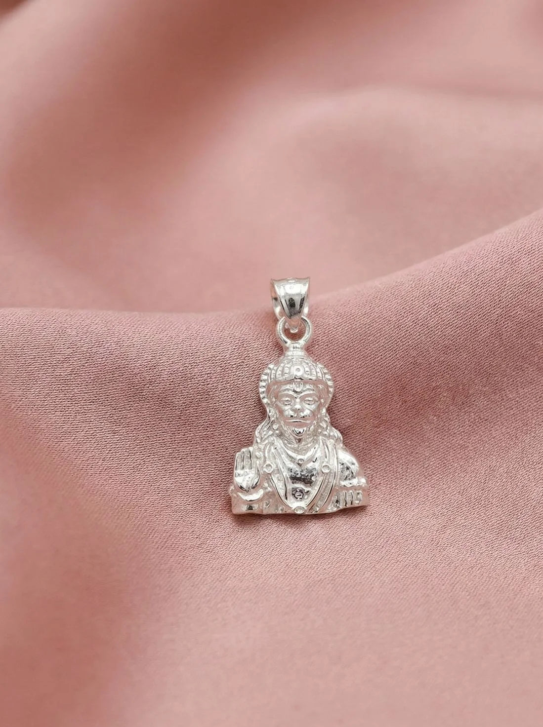 Silver Buddha pendant on a pink fabric background