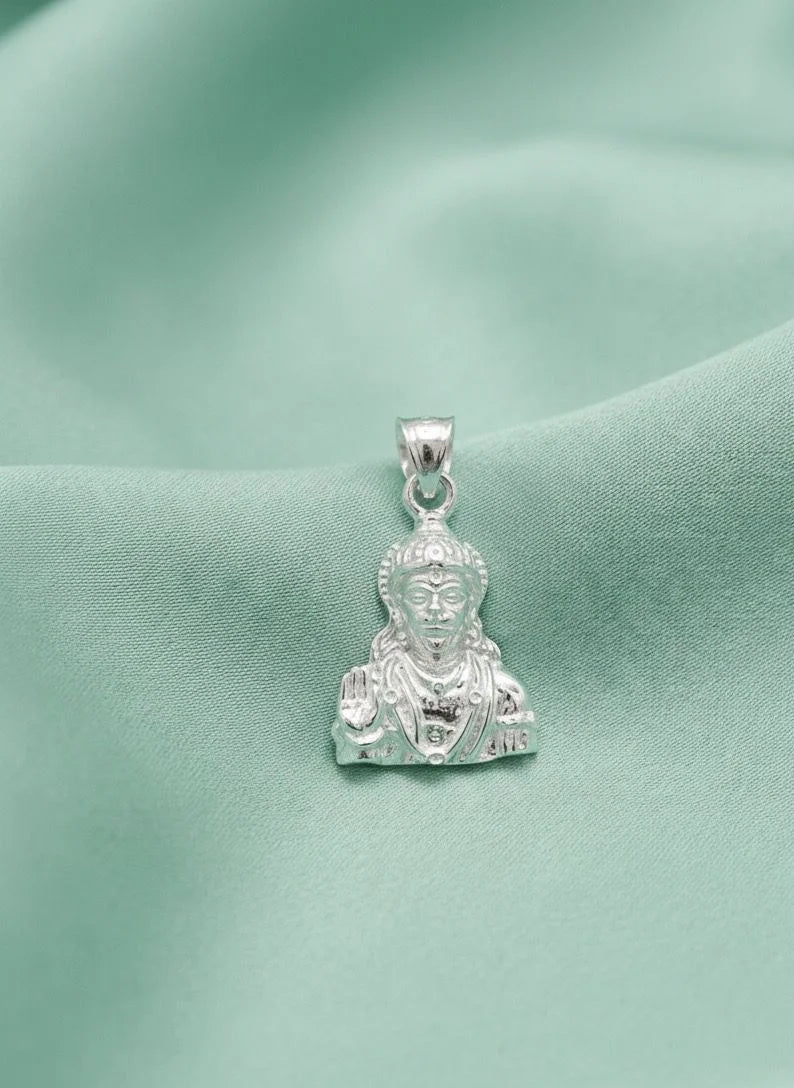 Silver pendant with a face design on a green fabric background