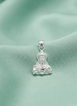 Silver pendant with a face design on a green fabric background