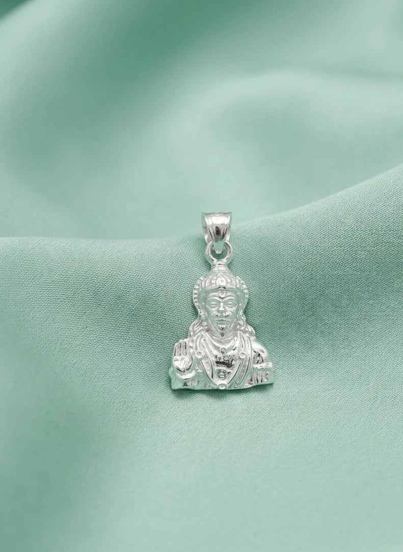 Silver pendant with a face design on a green fabric background