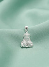 Silver pendant with a face design on a green fabric background