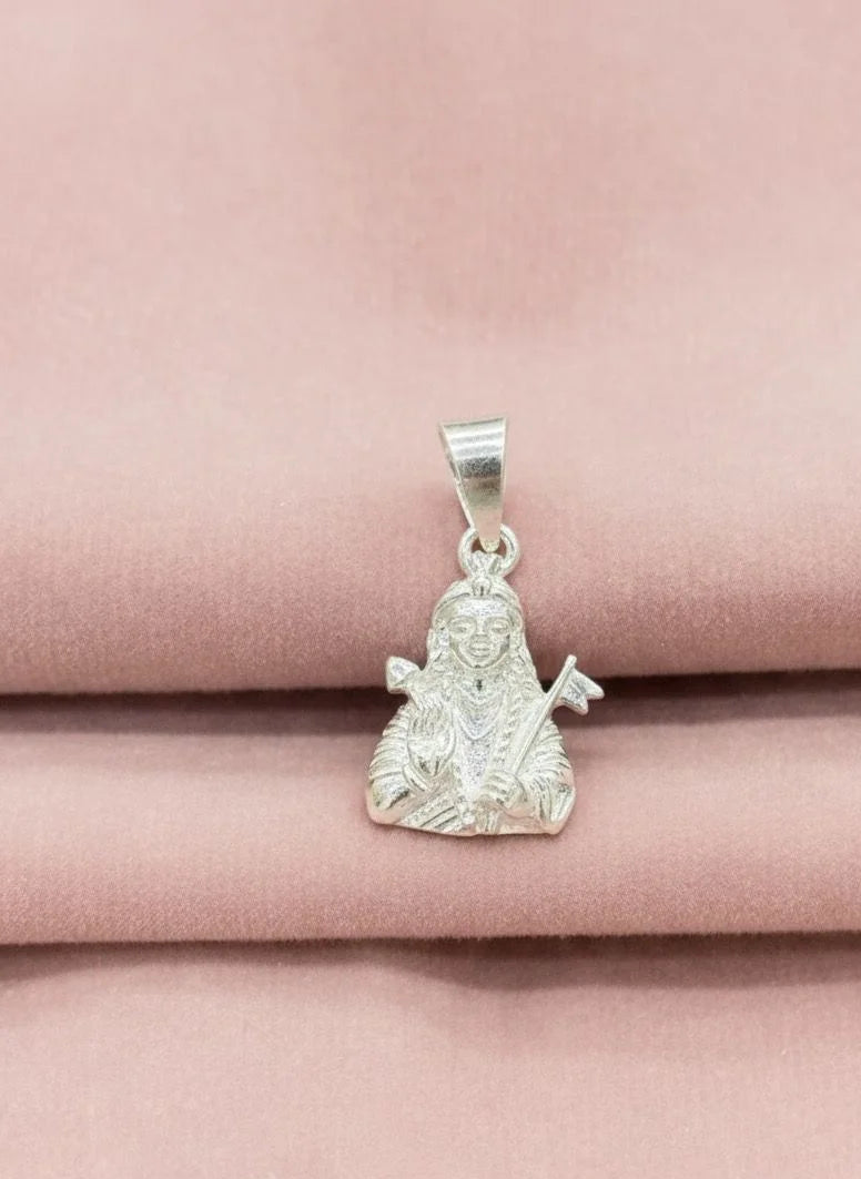 Silver pendant with a religious figure on a pink fabric background