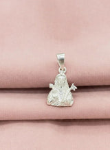Silver pendant with a religious figure on a pink fabric background