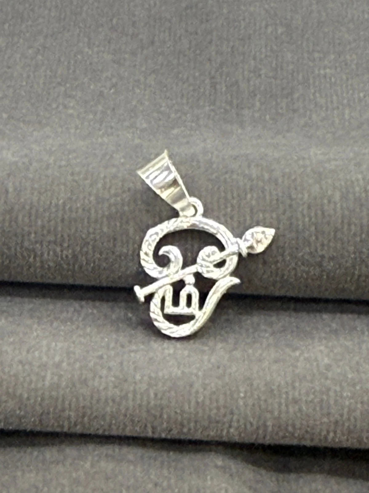 Silver pendant on a gray fabric background