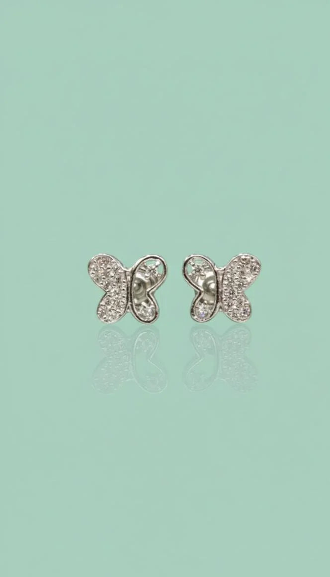 Butterfly-shaped earrings on a light green background