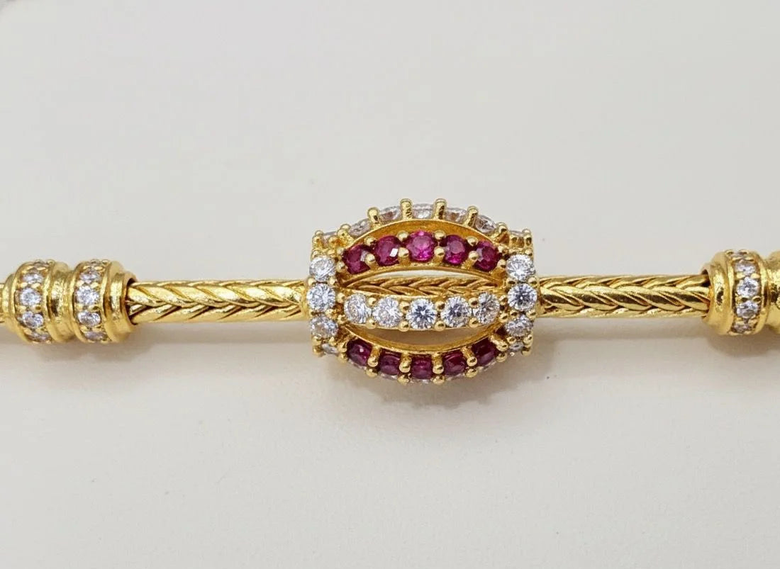 Gold mugappu chain with red gemstones and clear stones on a light gray background