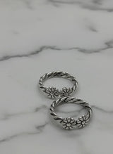 Silver toe ring with floral designs on a marble surface