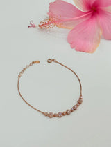 Rose gold bracelet with pink flower on light gray background
