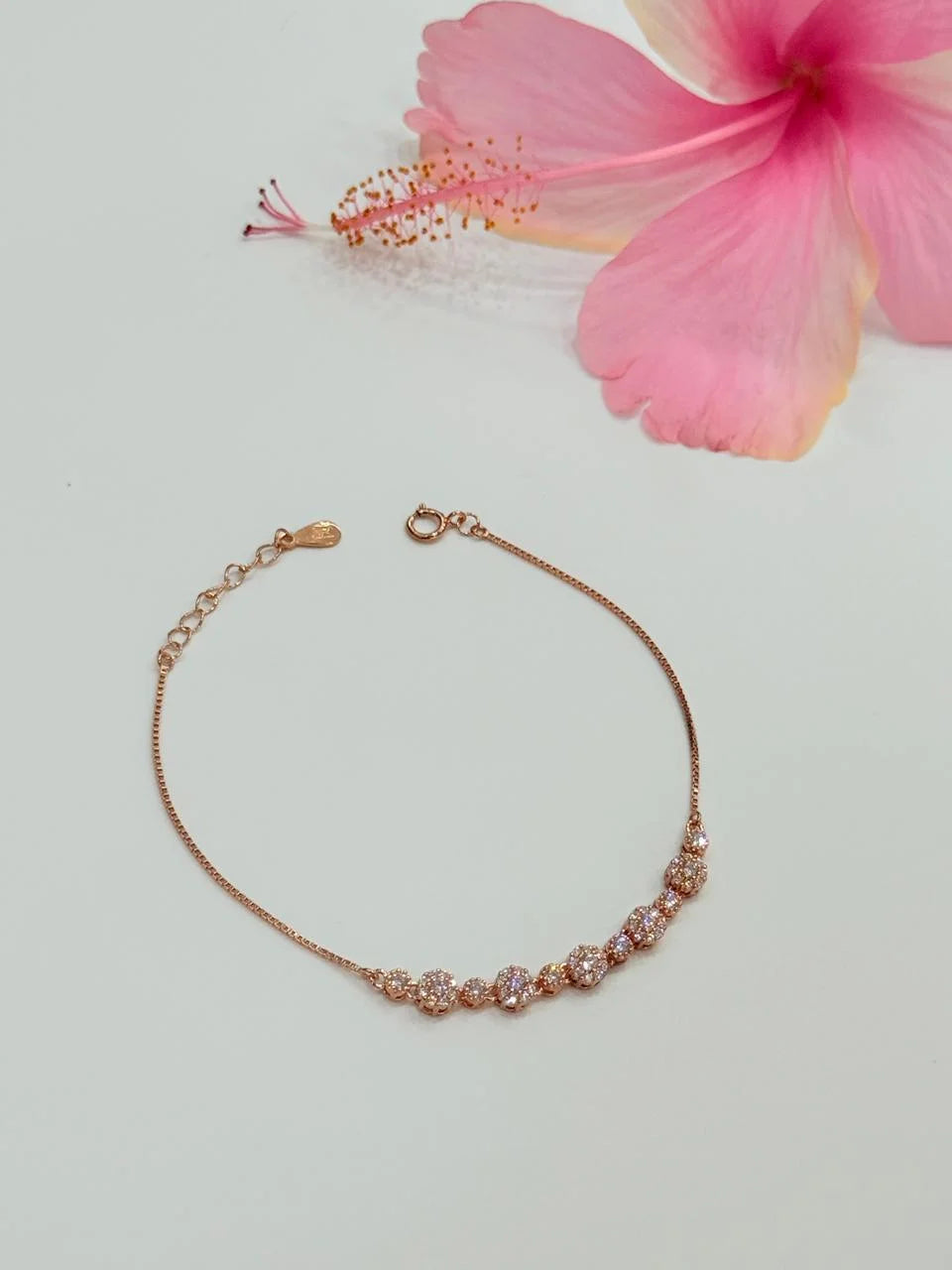 Rose gold bracelet with pink flower on light gray background
