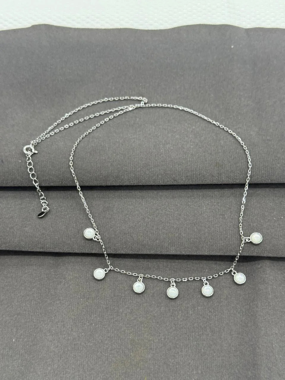 Silver necklace with round pendants on a gray surface