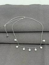 Silver necklace with round pendants on a gray surface