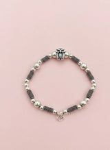Beaded bracelet with an owl charm on a pink background