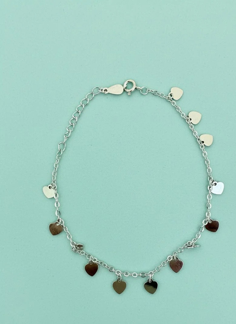 Silver bracelet with heart-shaped charms on a light blue background